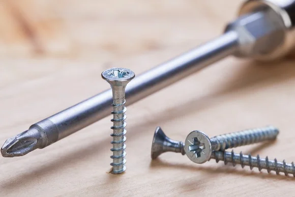 Schraubenzieher und Schrauben auf Holz